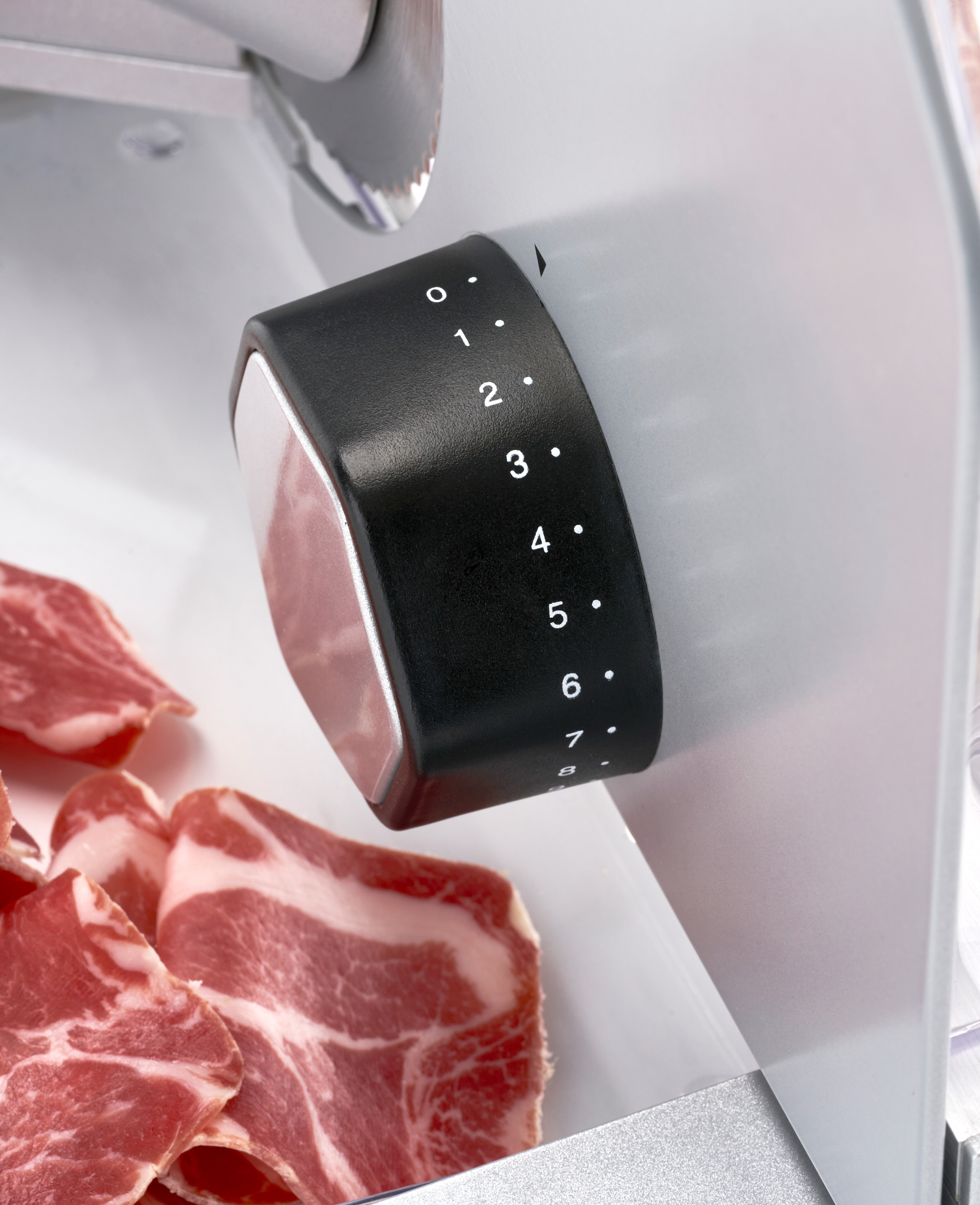 Un cadran noir avec des chiffres et des tranches de viande sur une trancheuse, gros plan.