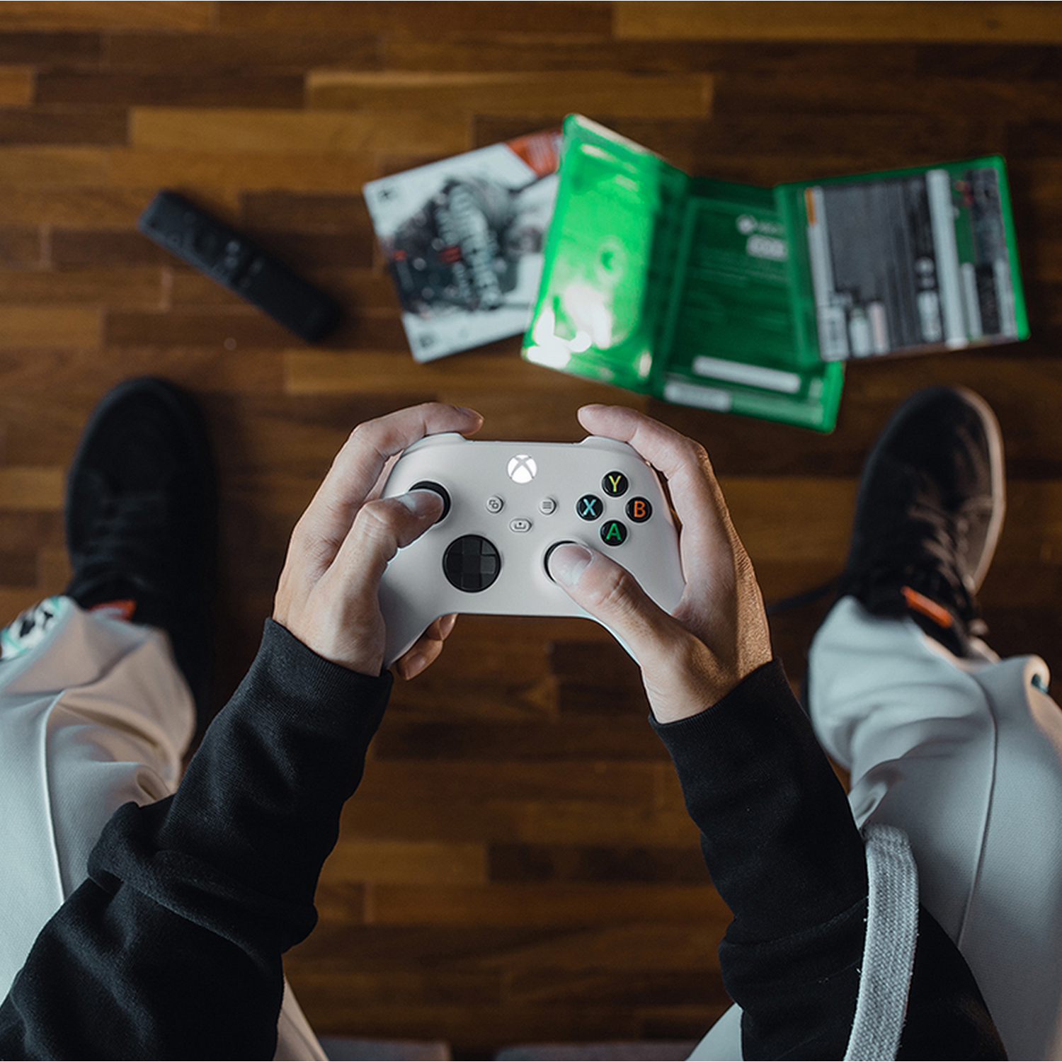 Handen die een witte Xbox-controller vasthouden boven een houten oppervlak.