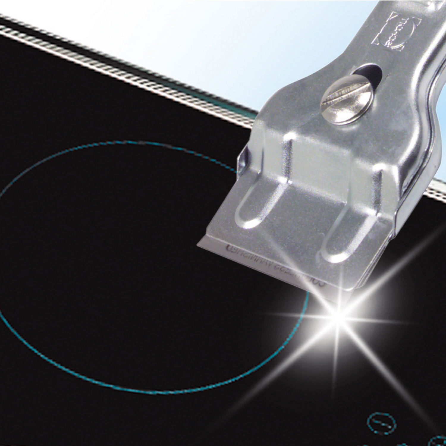 Close-up of a scraper on a black stovetop with a blue ring.