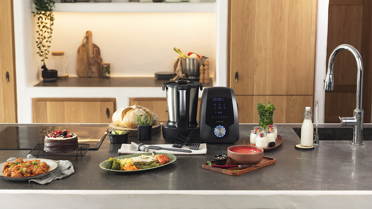 Encimera de cocina con varios platos, robot de cocina y grifo al fondo.