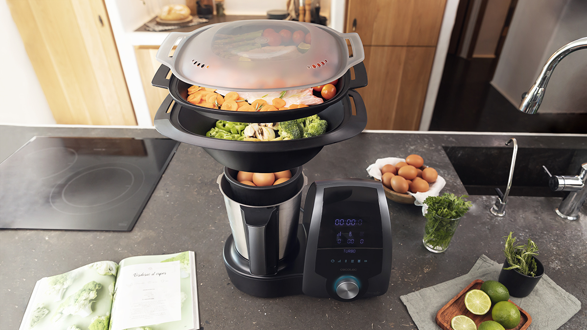 Una máquina para cocinar con comida dentro, más ingredientes en la encimera, mostrando la preparación.