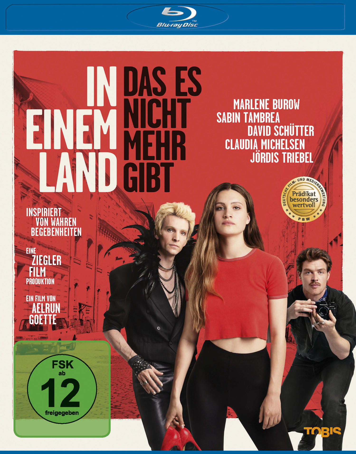 Filmposter: Drei Personen. Text: In das es nicht mehr Einem Land gibt. Rote, weiße und schwarze Farben.