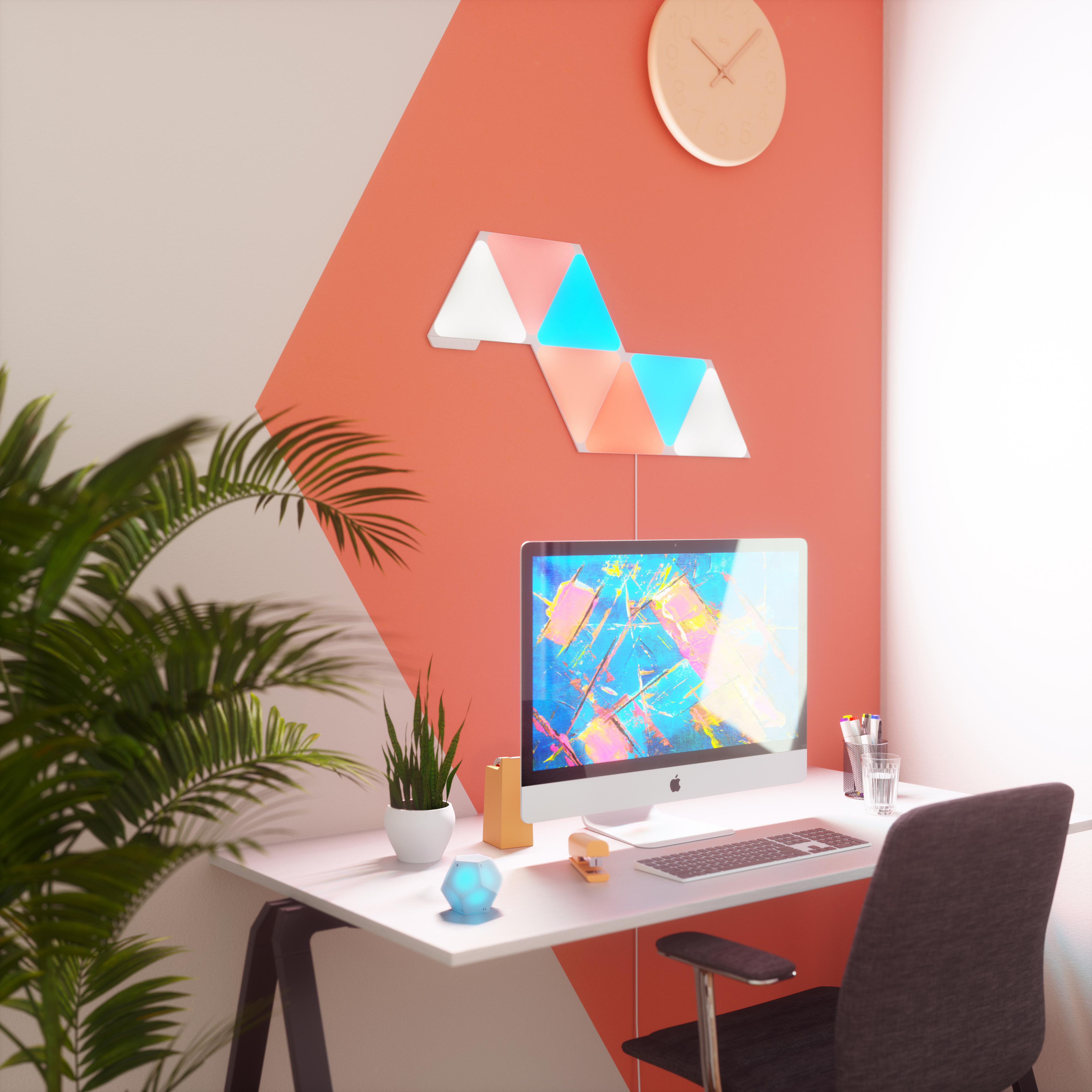 Moderner Bürotisch mit Computer, Lichtern und Pflanzen.