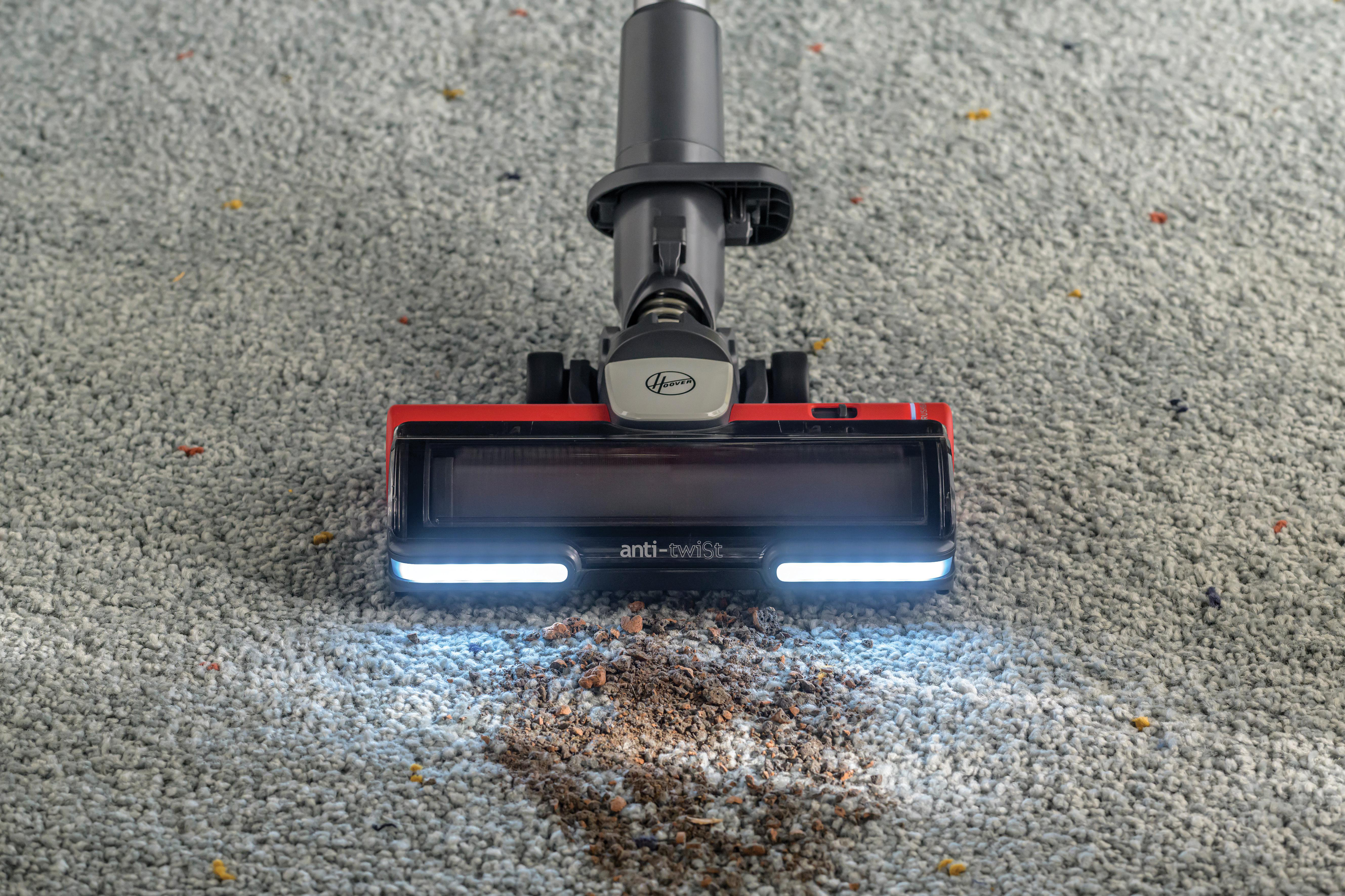 Staubsaugerkopf auf einem Teppich. Zeigt, wie Schmutz aufgesaugt wird. Hat helle Lichter.