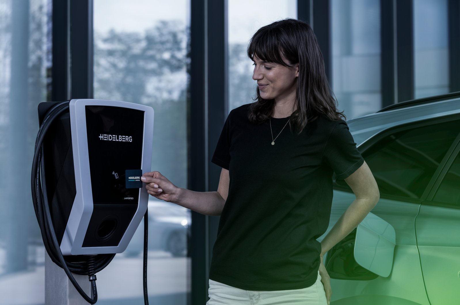 Frau hält eine Karte in der Nähe eines Ladegeräts für Elektroautos.