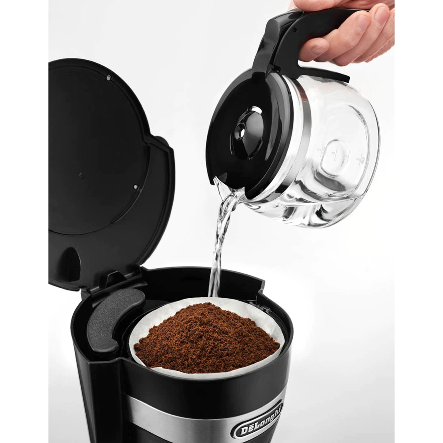L'acqua viene versata da una caraffa di vetro in una caffettiera.