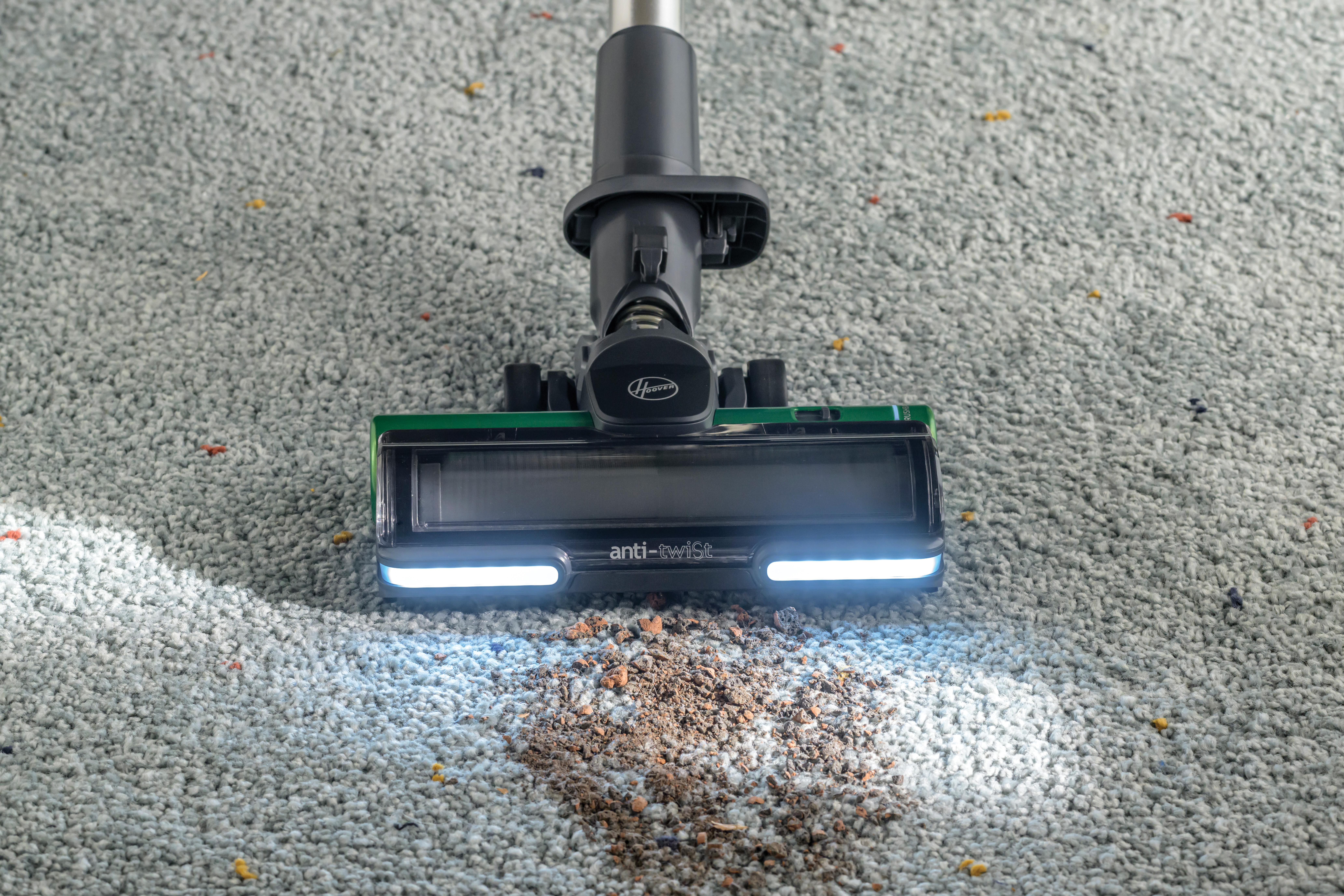 Vakuumkopf auf Teppich. Schmutzhaufen vorhanden. Marke Hoover sichtbar.