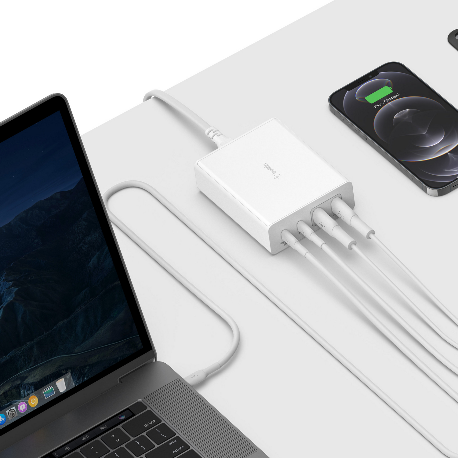 White charging station with multiple charging cables, connected to a laptop and phone.