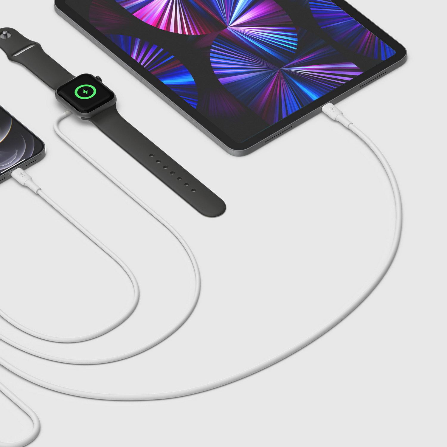Black Apple Watch, phone, and iPad connected with white cables. Watch shows charging icon. Background is white.