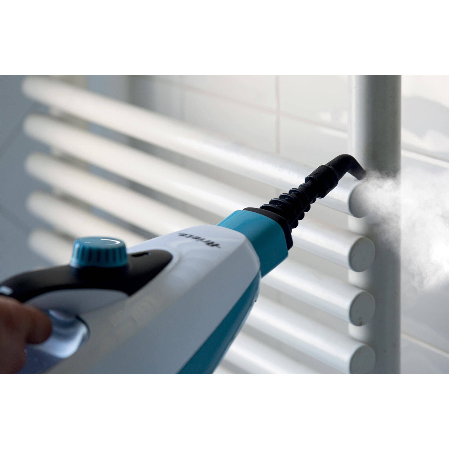 Un pulitore a vapore viene utilizzato su un termosifone bianco. Il vapore è visibile.