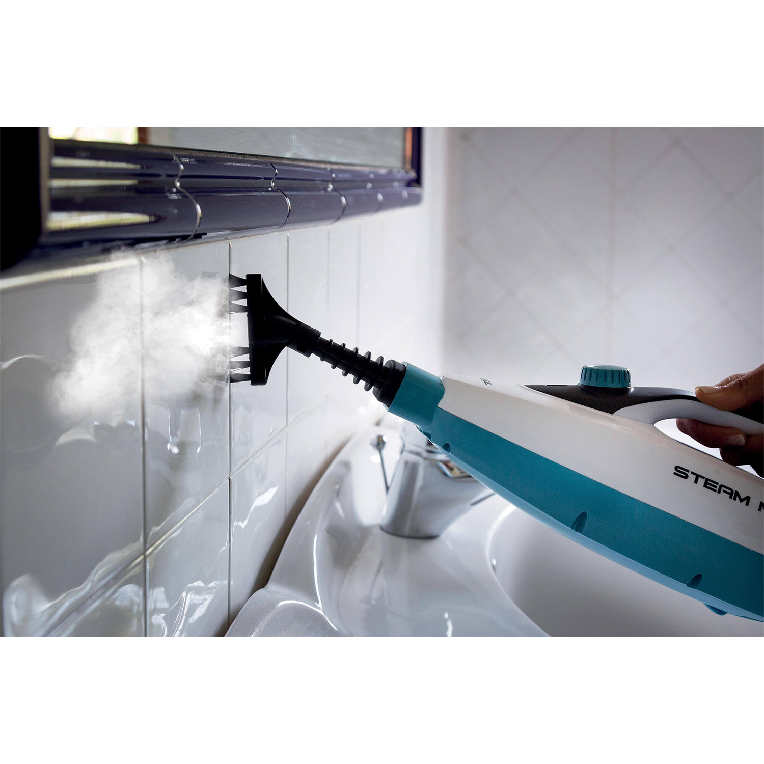 Una persona pulisce piastrelle bianche in un bagno con un pulitore a vapore. Il vapore è visibile.