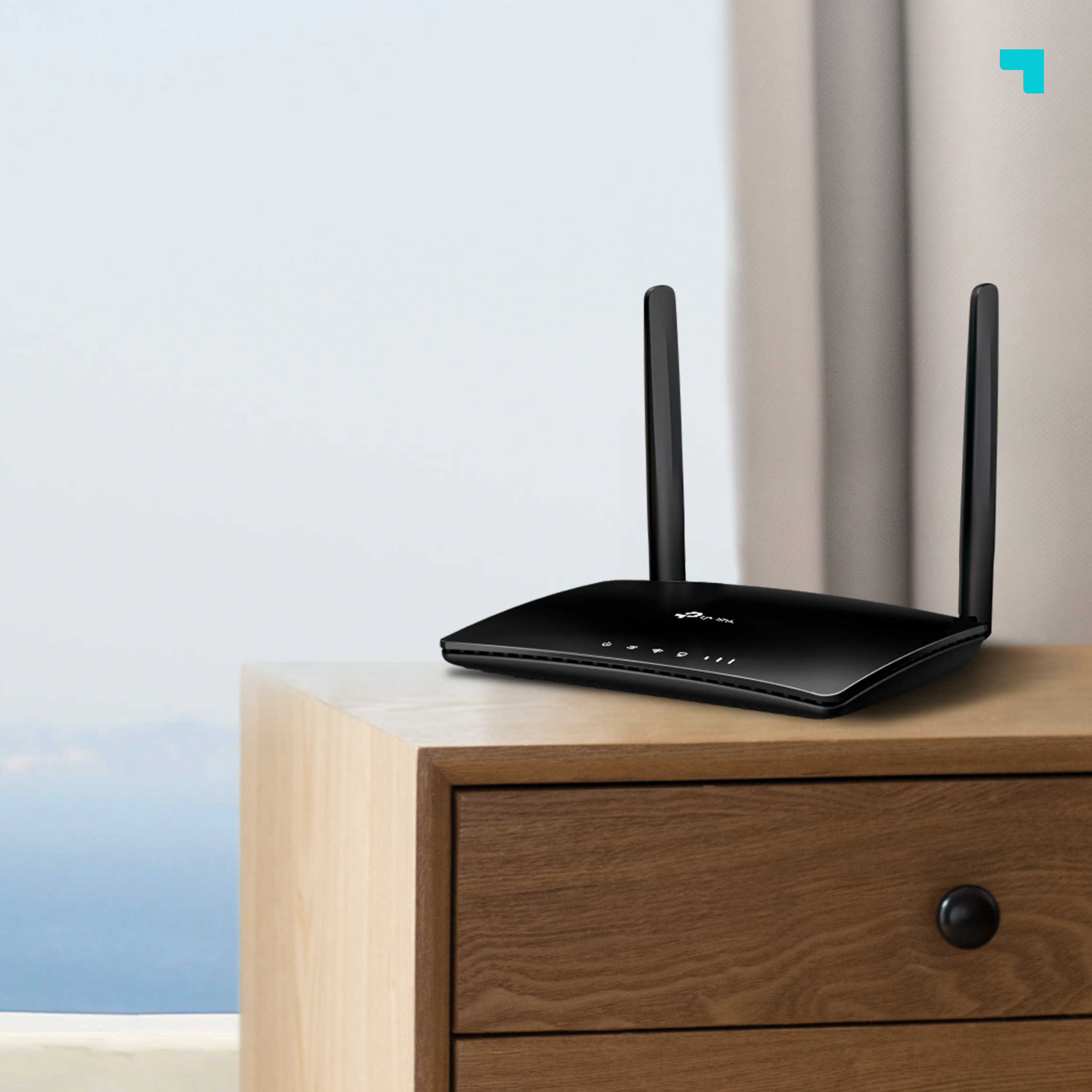 Router TP-Link negro con dos antenas sobre una mesita de noche de madera cerca de una ventana.
