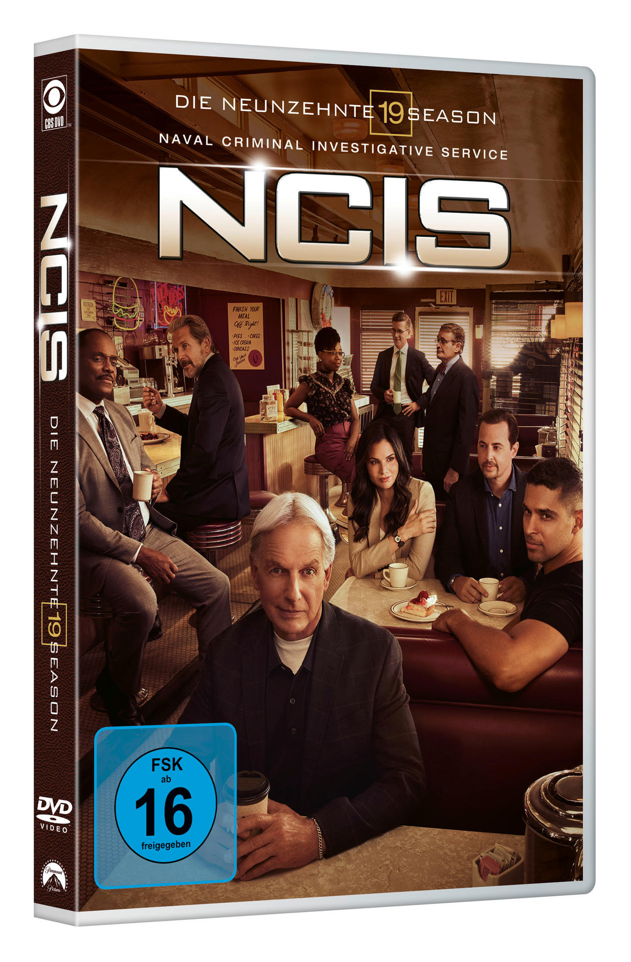 Boîtier DVD NCIS avec un groupe d'acteurs dans un cadre de restauration. Le fond est sombre.
