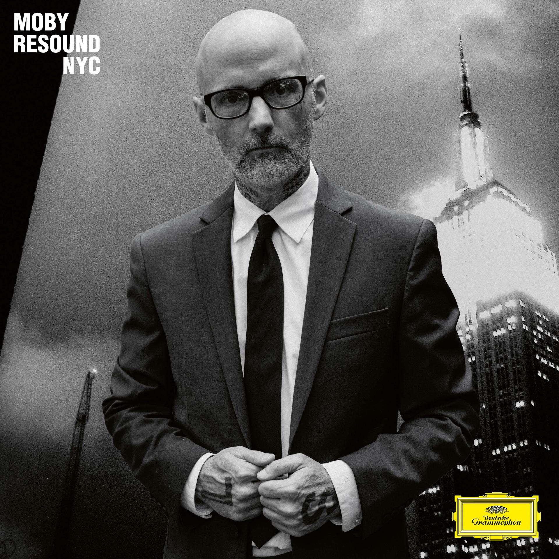Moby in pak en stropdas, met Empire State Building op de achtergrond. Albumhoes 'Resound NYC'.