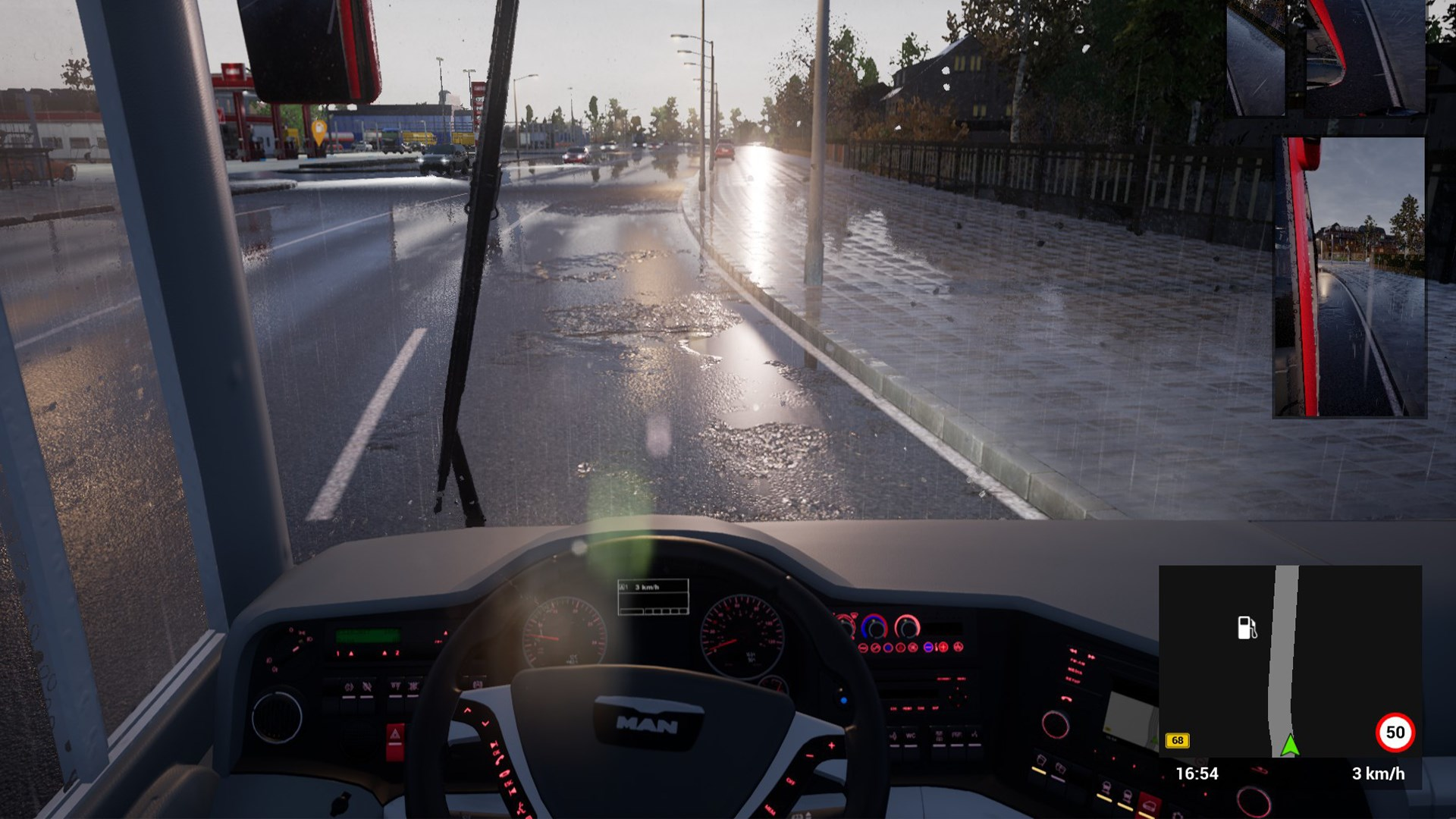 Vue de l'intérieur d'un bus roulant sur une route mouillée. Les essuie-glaces sont actifs. Bâtiments et panneau routier visibles.