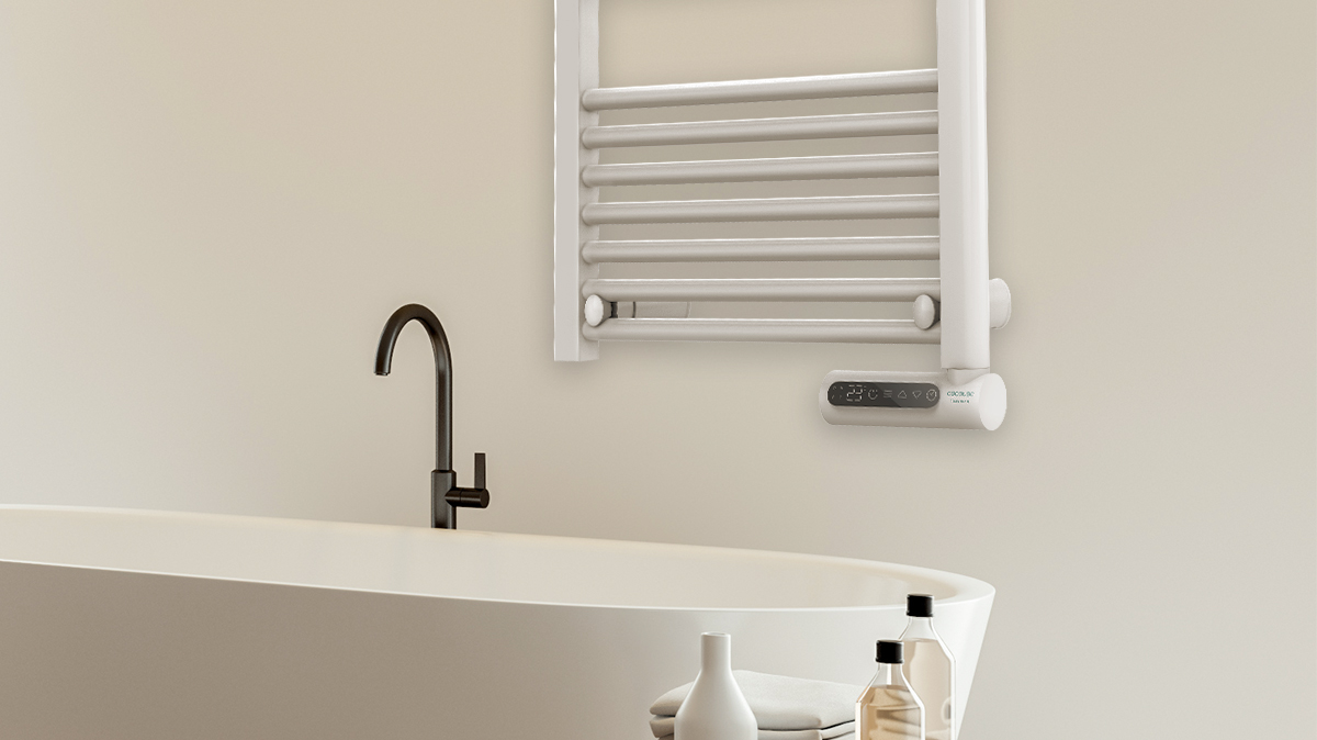 Una escena de baño con una bañera blanca, un grifo negro y un toallero. Hay botellas delante de la bañera.
