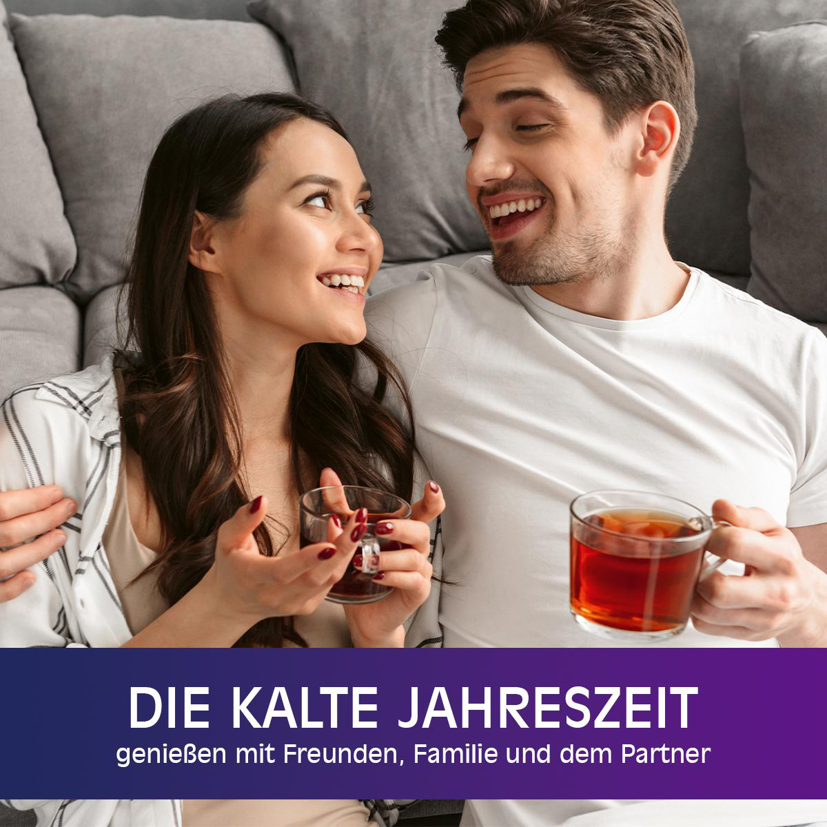 Ein lächelndes Paar hält Teetassen. Der Hintergrund ist ein gemütliches Wohnzimmer.