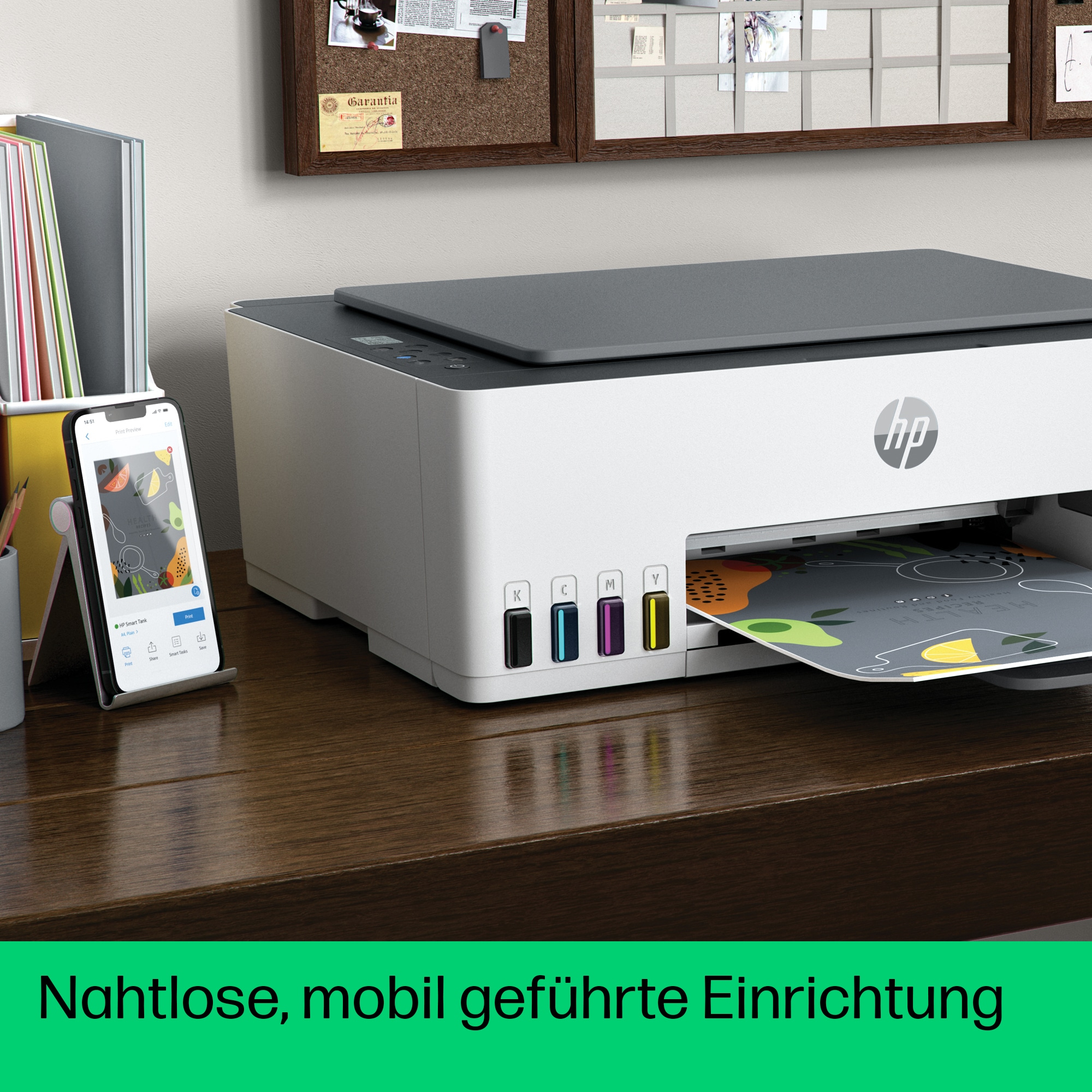 Drucker auf einem Schreibtisch, mit Telefon, das eine App zeigt, links.