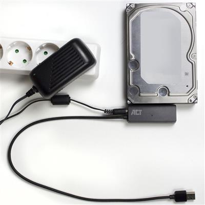 Adaptateur secteur avec câble connecté à un disque dur et une prise de courant. L'installation est sur une surface blanche.