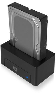 A black hard drive is inserted into a black docking station with a blue light.