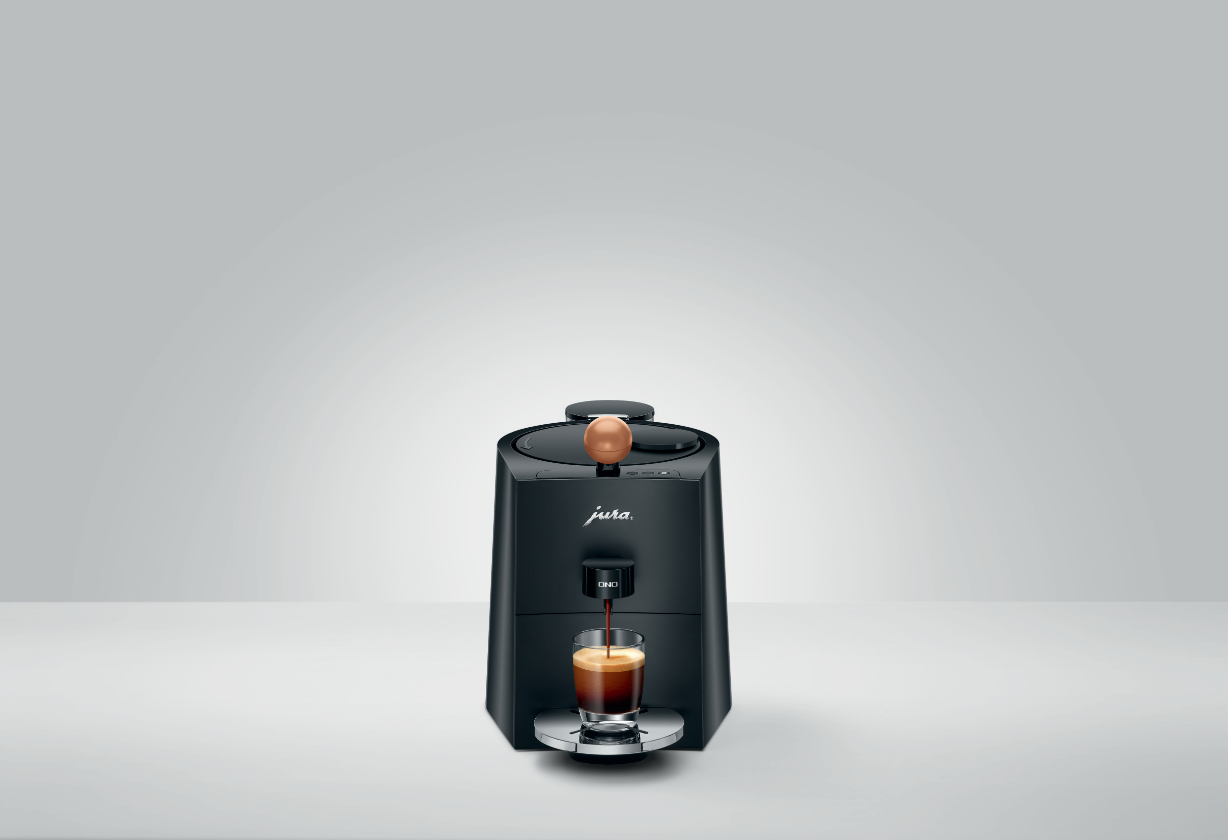 Schwarze Jura Kaffeemaschine mit einem Glas Espresso.