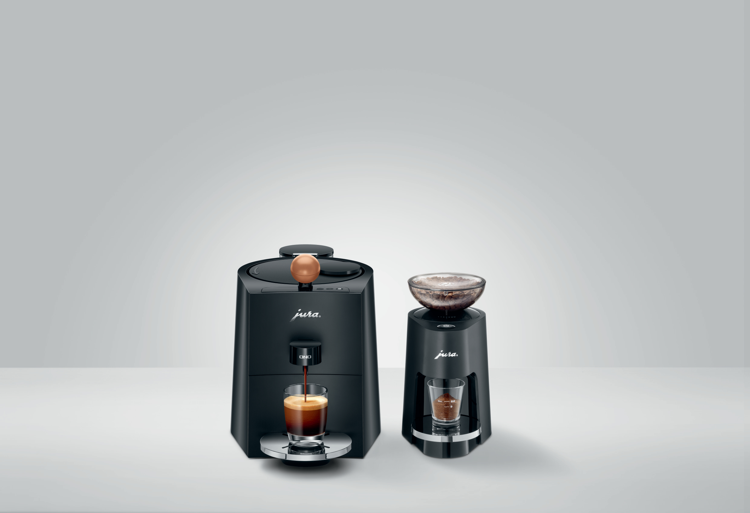Zwei schwarze Kaffeemaschinen, eine mit Mahlwerk und Tasse, die andere mit Kaffee.