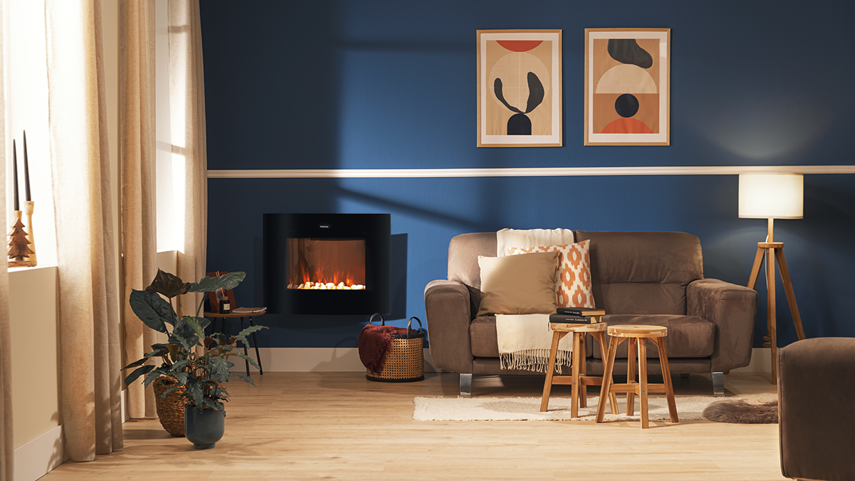 Salón con pared azul, chimenea, sofá marrón, arte y taburetes de madera. Plantas, cortinas y lámpara completan la escena.