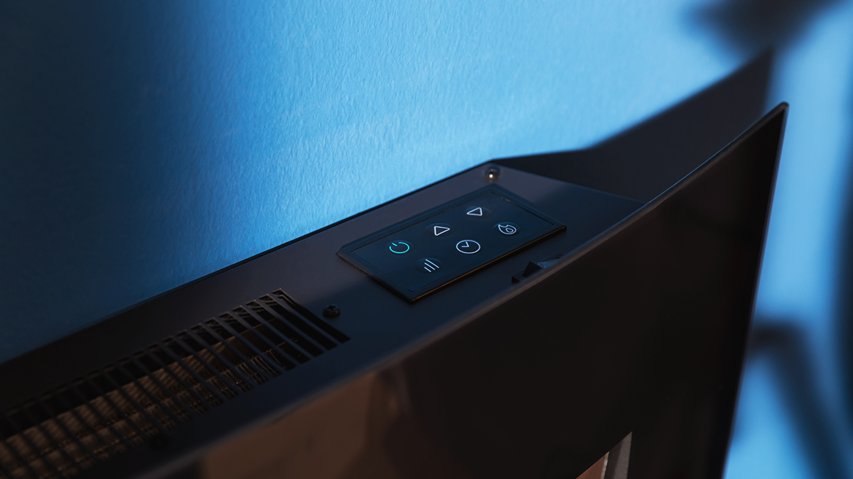 Primer plano de un panel de control negro con símbolos iluminados sobre una superficie negra. Una pared azul está en el fondo.