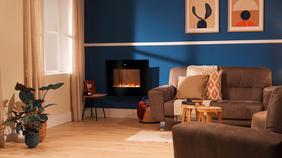 Salón con sofá marrón, chimenea, obras de arte y planta. Pared azul y suelo de madera. Interior brillante y acogedor.