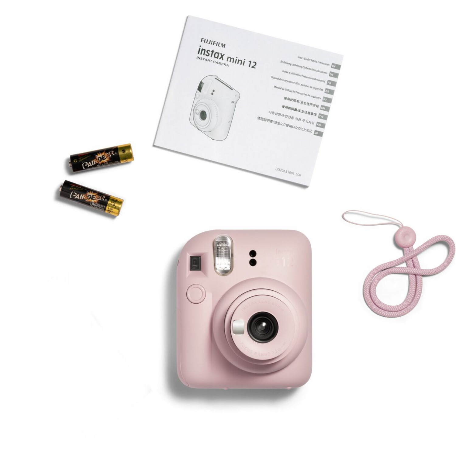 Roze Instax Mini 12 camera met accessoires: handleiding, batterijen en een roze riem. Witte achtergrond.