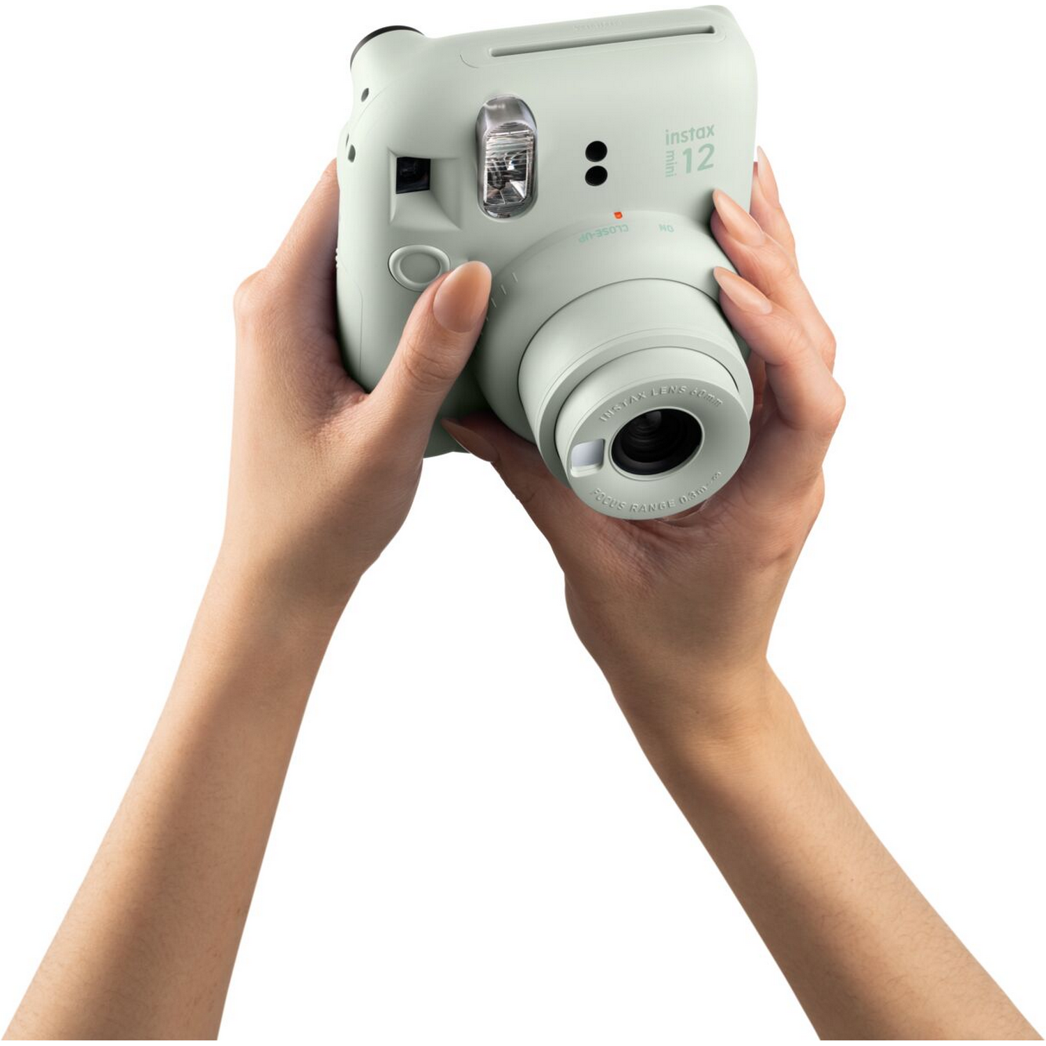 Handen die een mintgroene instax 12 camera vasthouden. Handen staan op de voorgrond.
