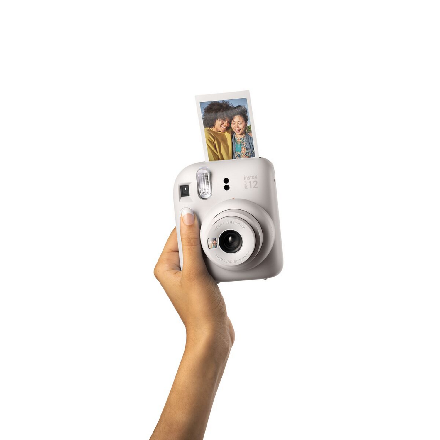 Hand die een witte Instax-camera met foto vasthoudt. Foto toont twee mensen. Witte achtergrond.