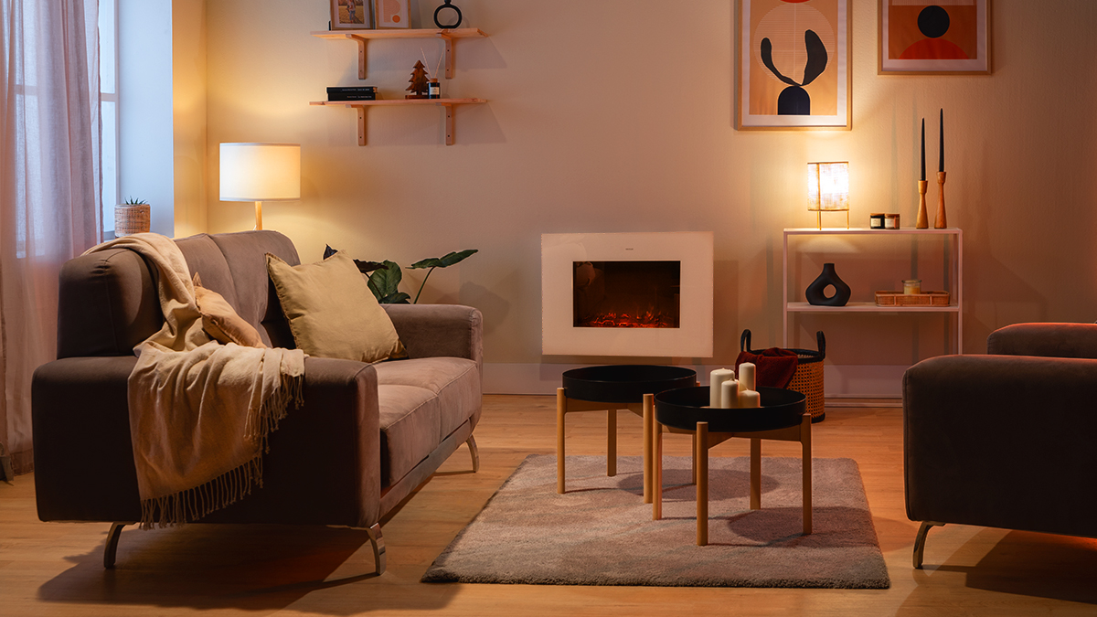 Salón con sofá, mesas de centro, chimenea, lámparas y obras de arte. La iluminación cálida crea un ambiente acogedor.