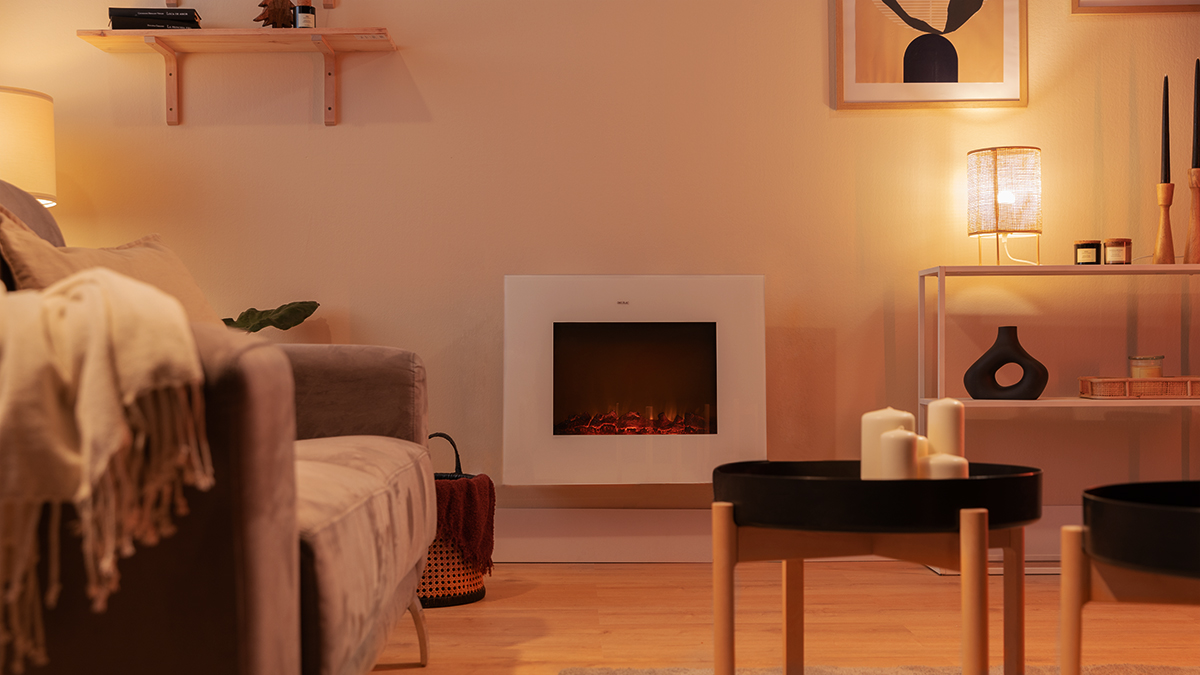 Salón con chimenea, sofá y mesa de centro. Velas decorativas y lámpara. Ambiente cálido y acogedor.