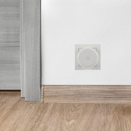 Weißer Smart Plug in einer Steckdose an einer weißen Wand installiert.
