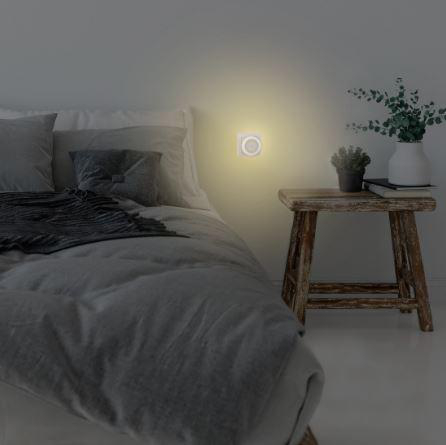 Ein Schlafzimmer bei Nacht, beleuchtet von einem sanften Licht einer Wand-Nachtleuchte.