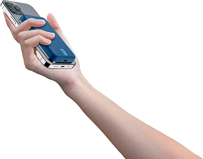 Mano sosteniendo un cargador portátil azul y plateado junto a un teléfono.
