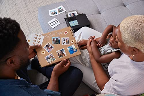 Familia mirando un álbum de fotos. Fotos expuestas. Impresora negra al fondo. Sofá gris.