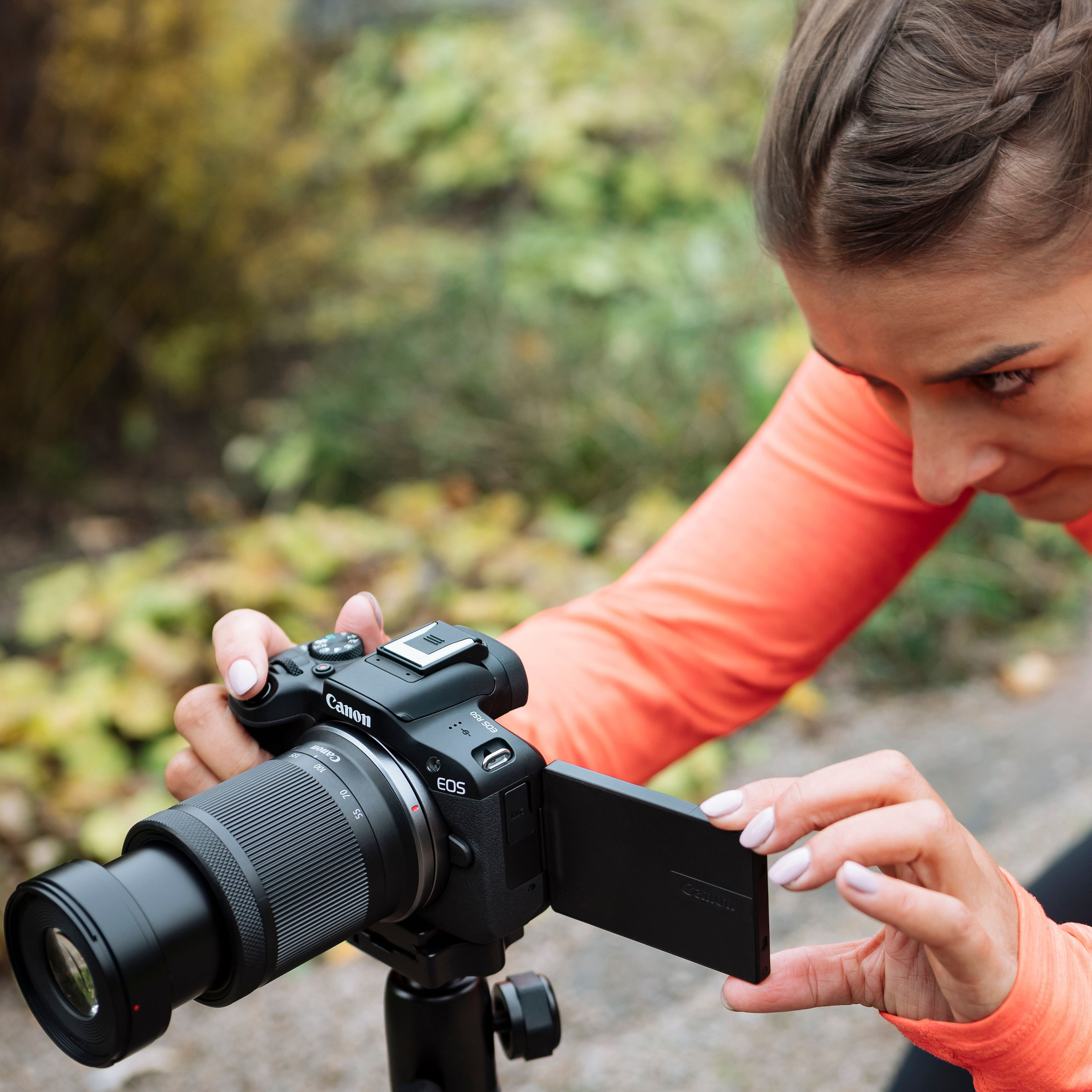 Femme regardant l'écran d'un appareil photo. L'appareil photo est noir avec un grand objectif.