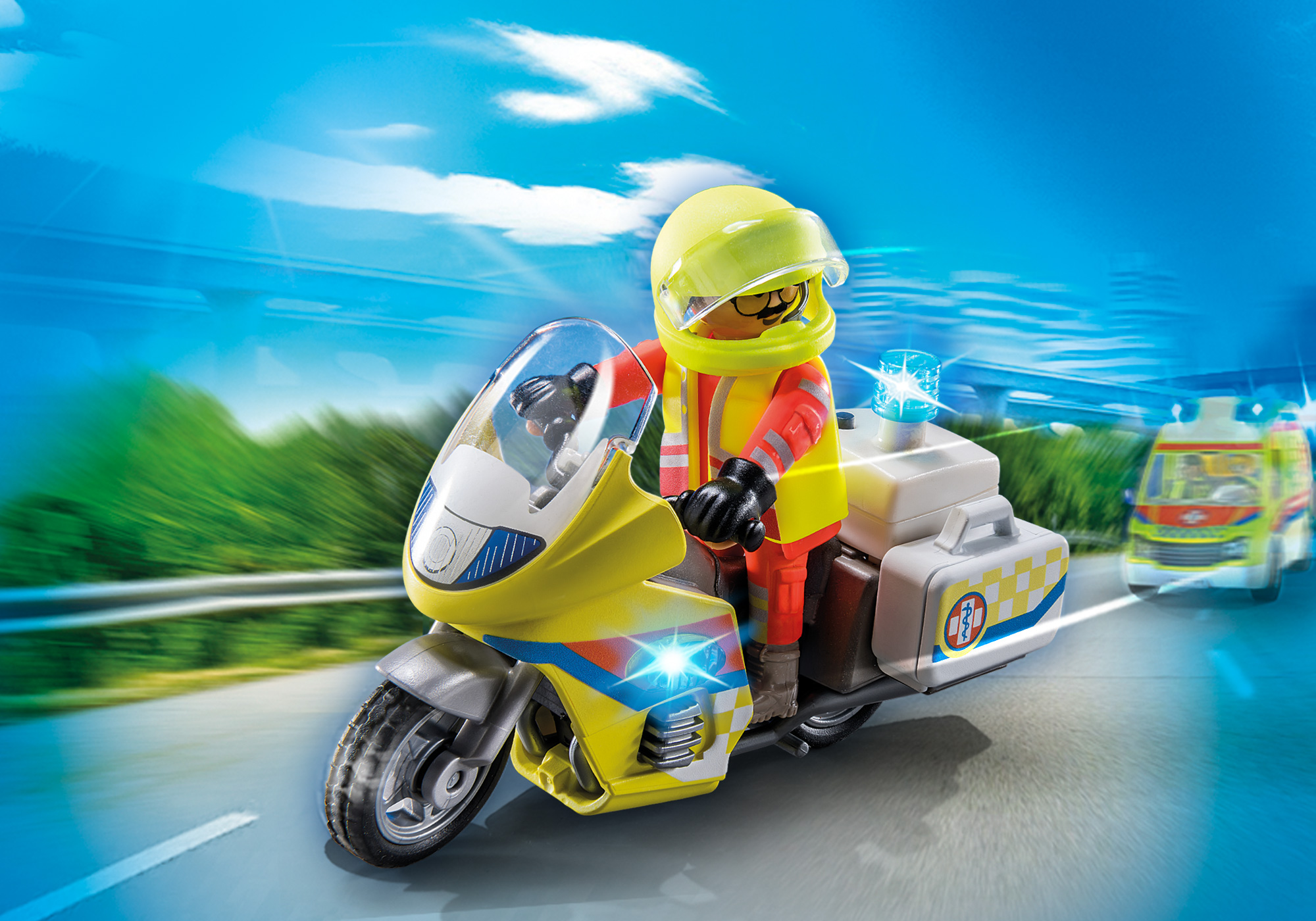 Ein Spielzeugmotorrad mit gelber Verkleidung und einer Figur mit Helm und Weste. Im Hintergrund ein Krankenwagen.