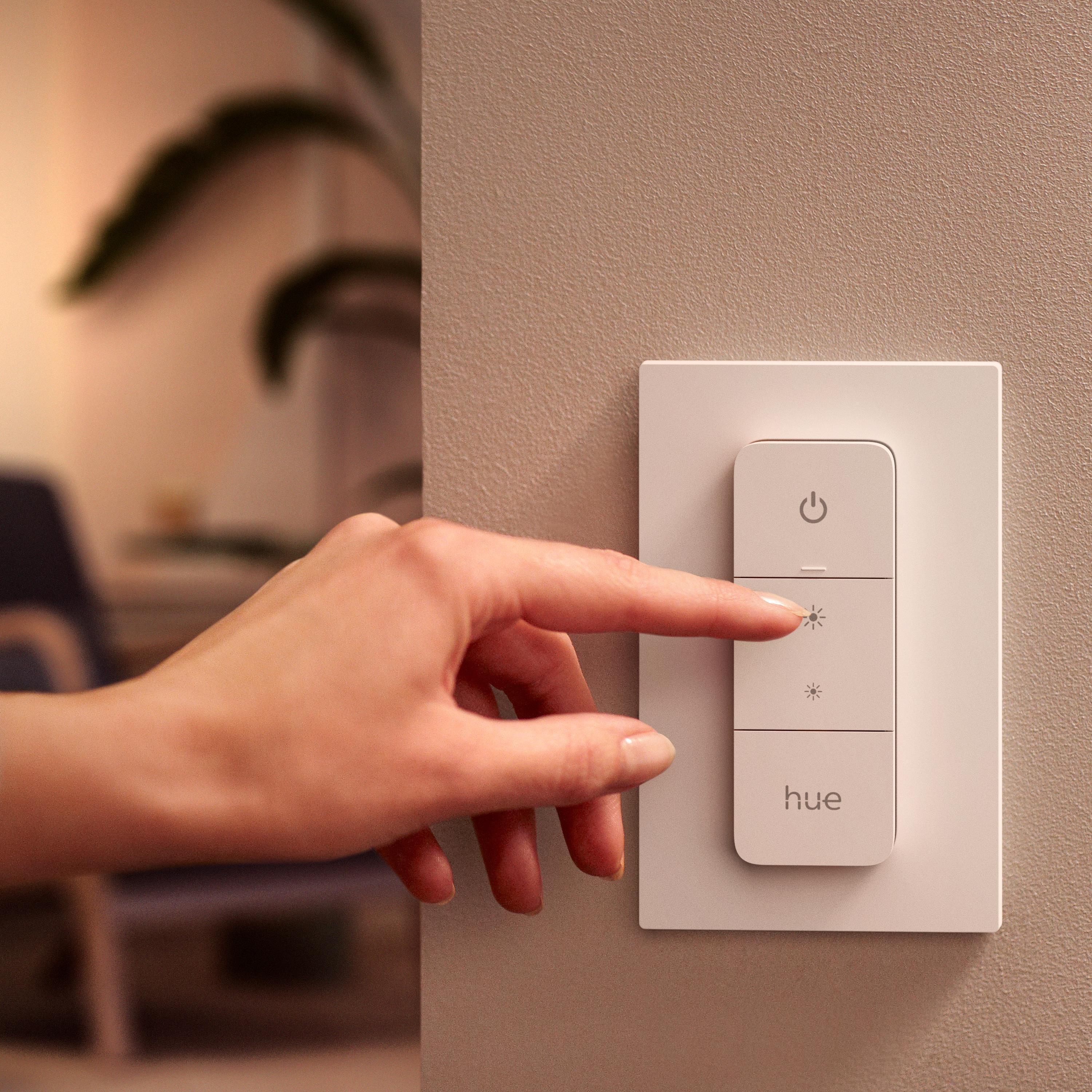 Hand drückt Lichtschalter mit drei Tasten: Strom, Licht und Dimmer.