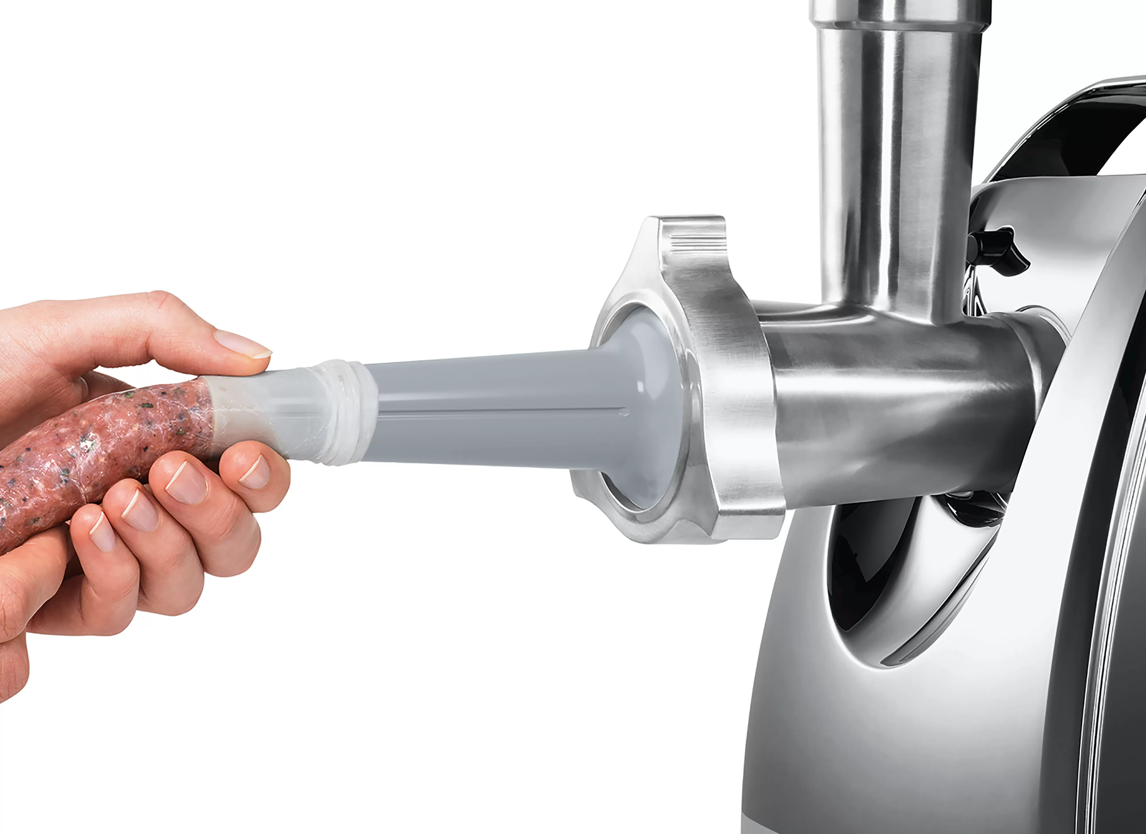 Egy kéz, amely egy kolbászt tart, amelyet egy húsdarálóba adagolnak.
