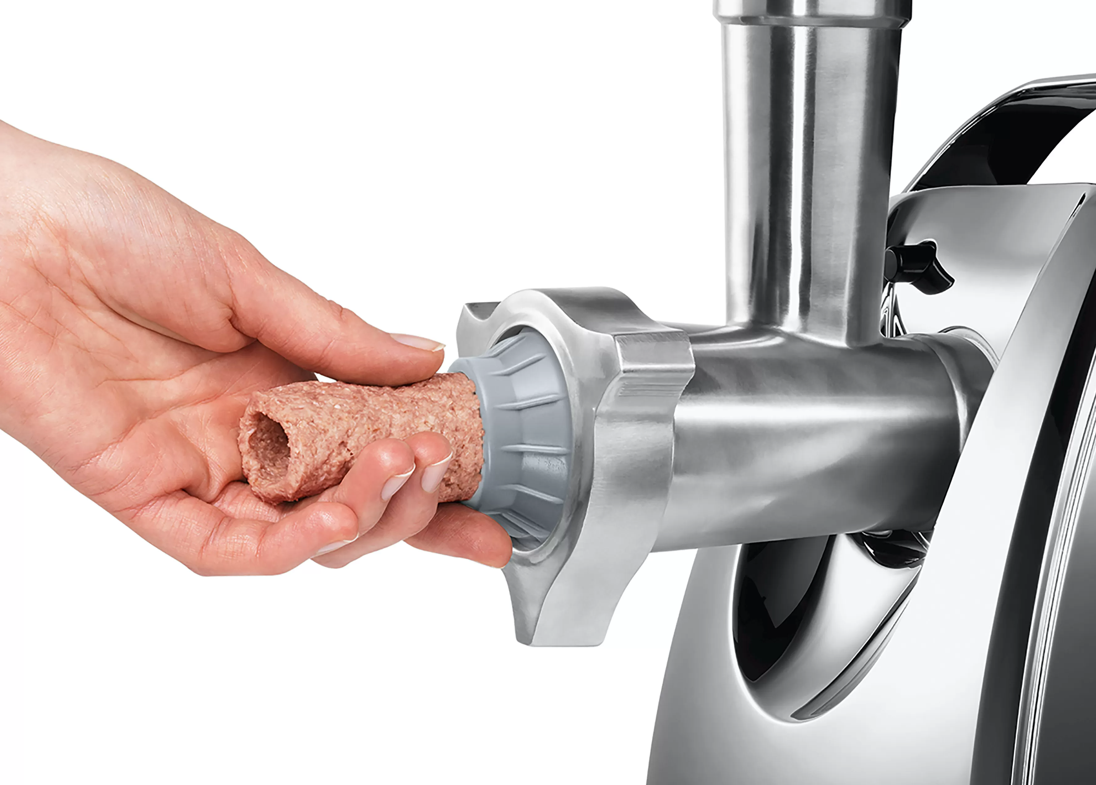 Egy kéz húsgombócot helyez egy ezüst húsdarálóba.