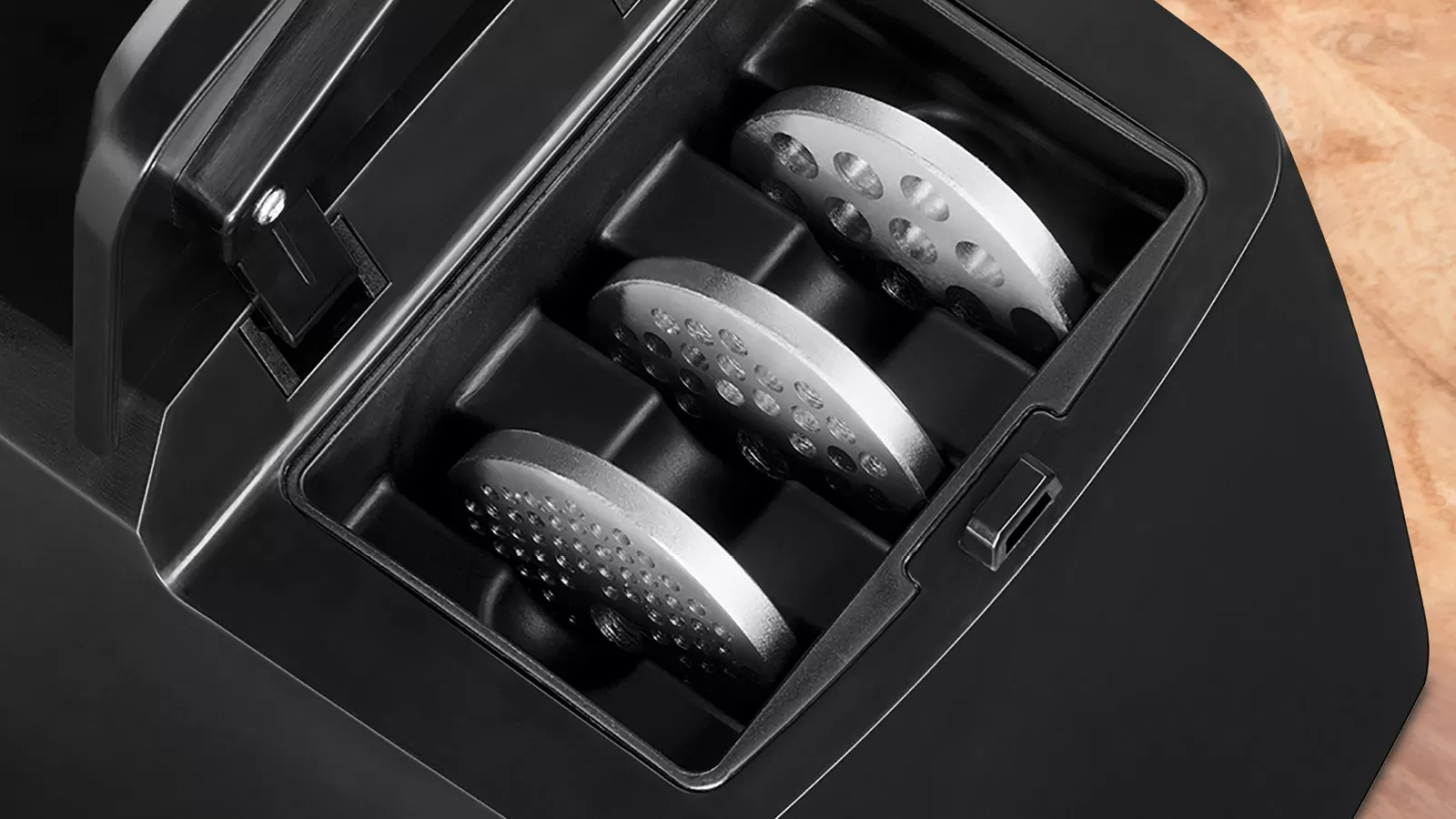 Közelkép egy fekete húsdarálóról, benne három acél darálólappal.