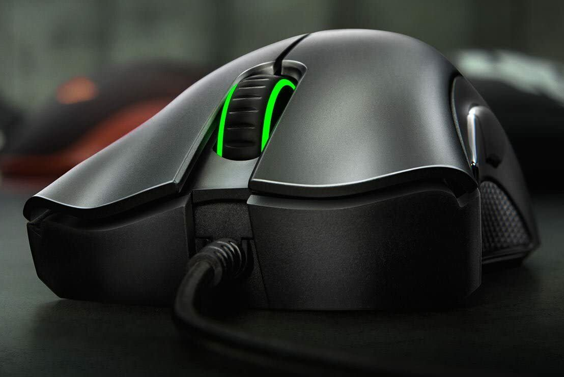 Fekete gamer egér zölden világító görgetőkerékkel. Az egér sötét felületen van.