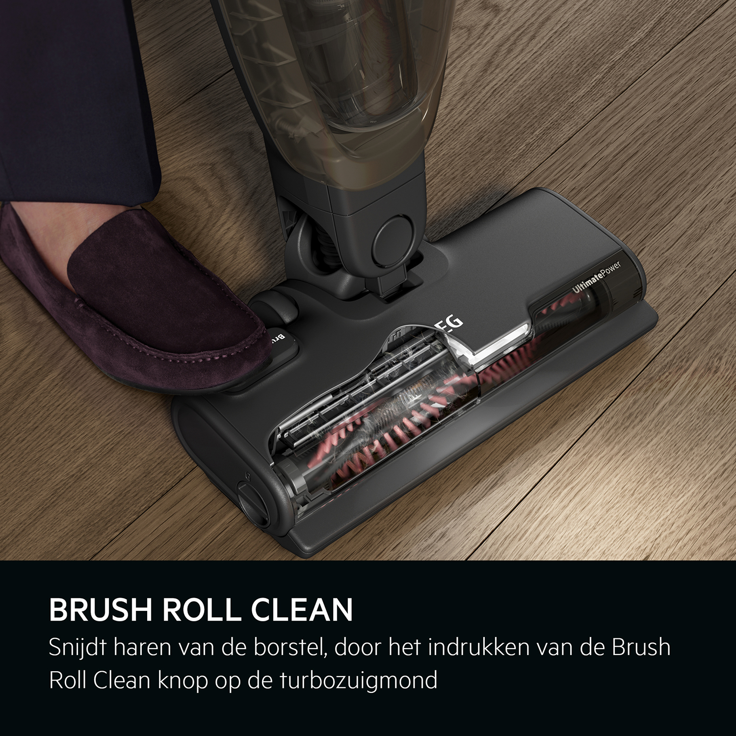 A person's foot wearing a shoe and the brush roll of a vacuum cleaner.