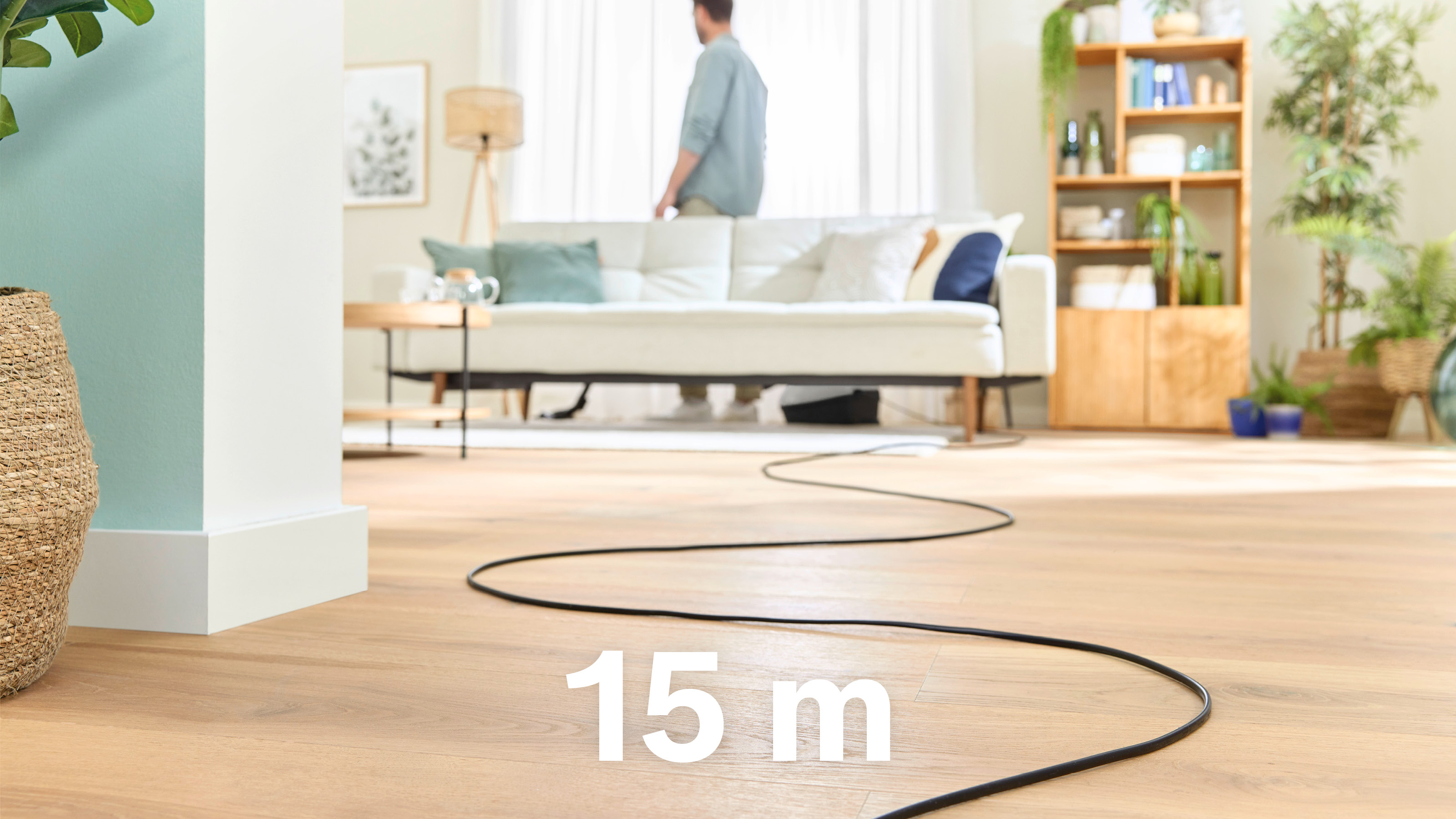 Ein 15 m langes schwarzes Kabel erstreckt sich über einen Holzboden, Person im Hintergrund.