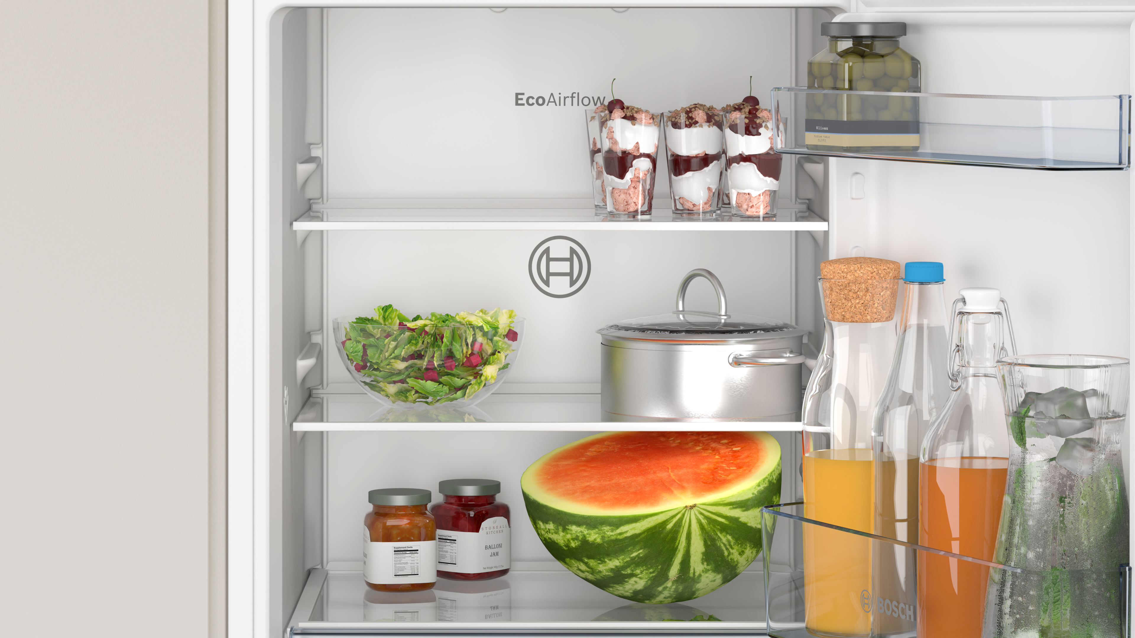 Kühlschrankinnenraum mit Lebensmitteln: Salate, Gläser, Wassermelone und Getränke.