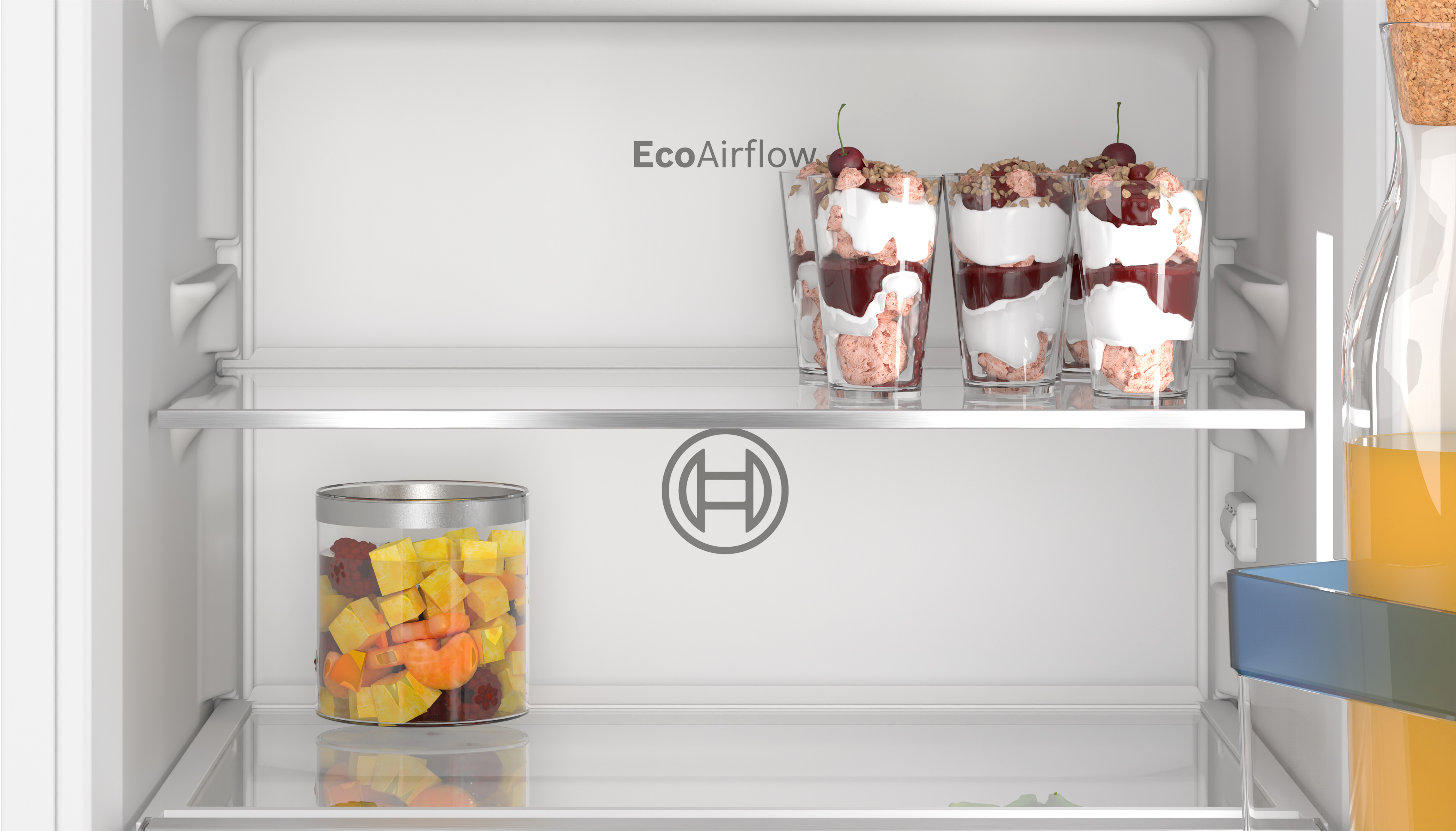 Innenseite eines weißen Kühlschranks. Es gibt Regale und Lebensmittel. Kirschparfaits und Obstsalat sichtbar.
