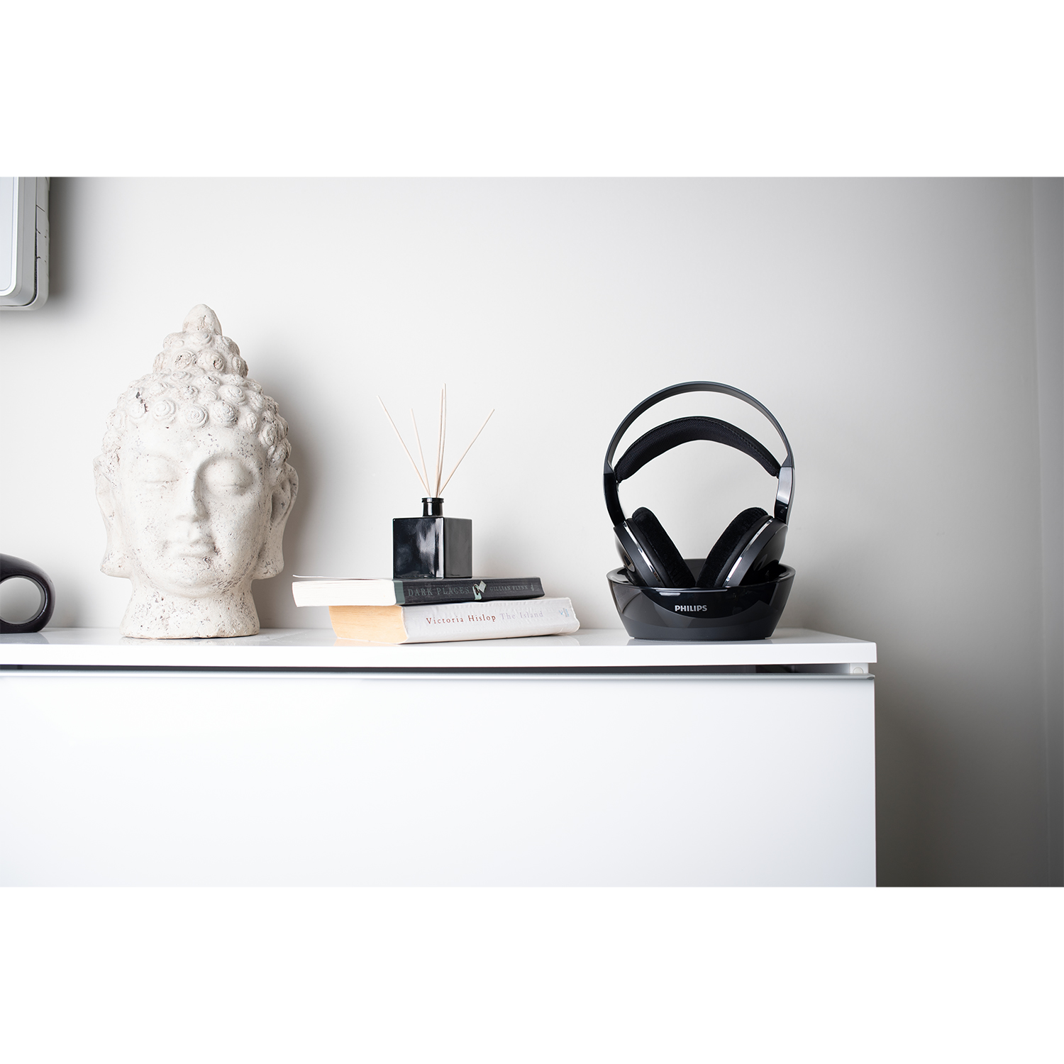 Cuffie nere su base nera, accanto a un Buddha e libri.